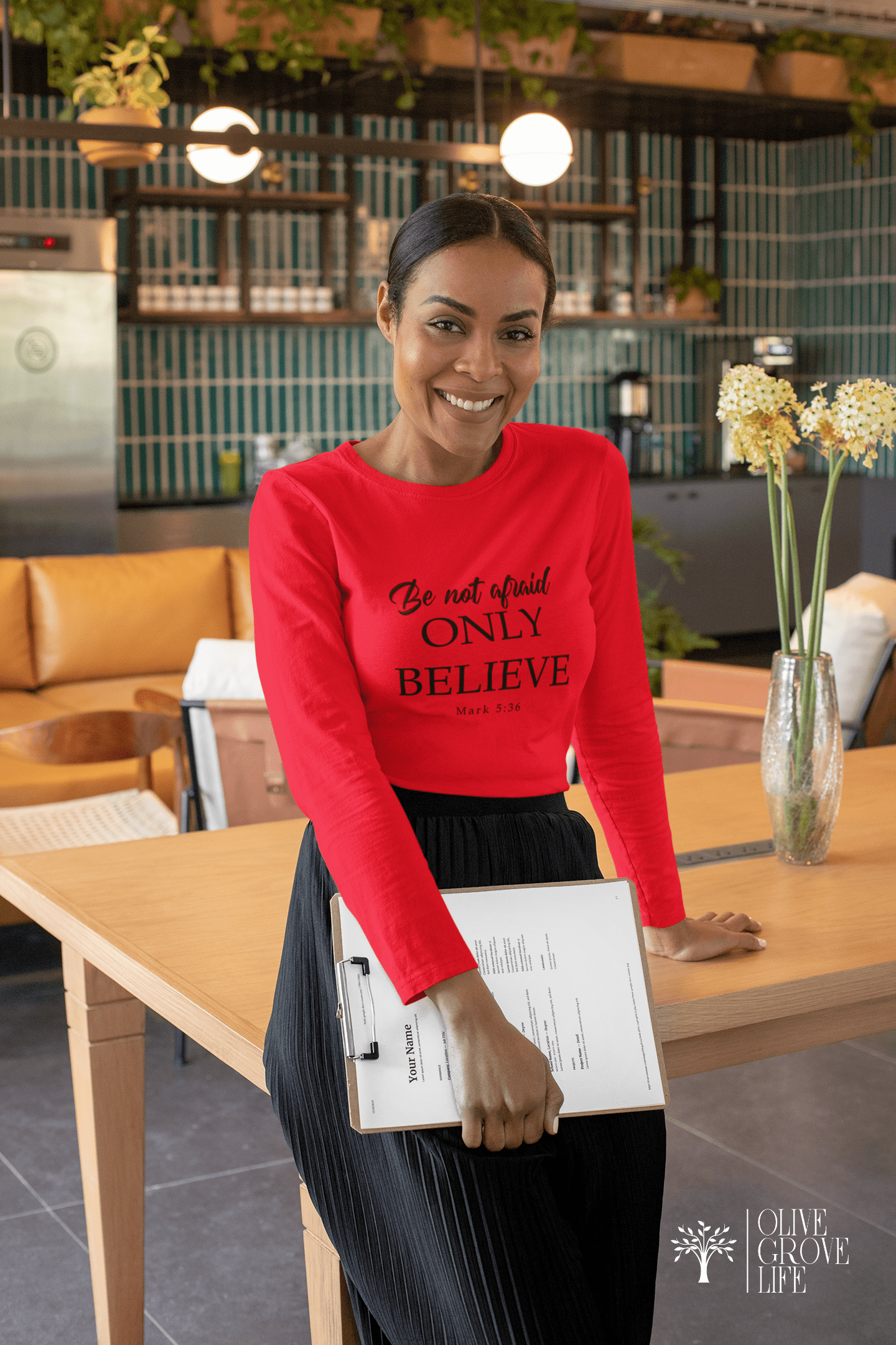 Mark 5:36 Be Not Afraid Only Believe Unisex Long Sleeve Tee Red on woman with clipboard leaning against a table