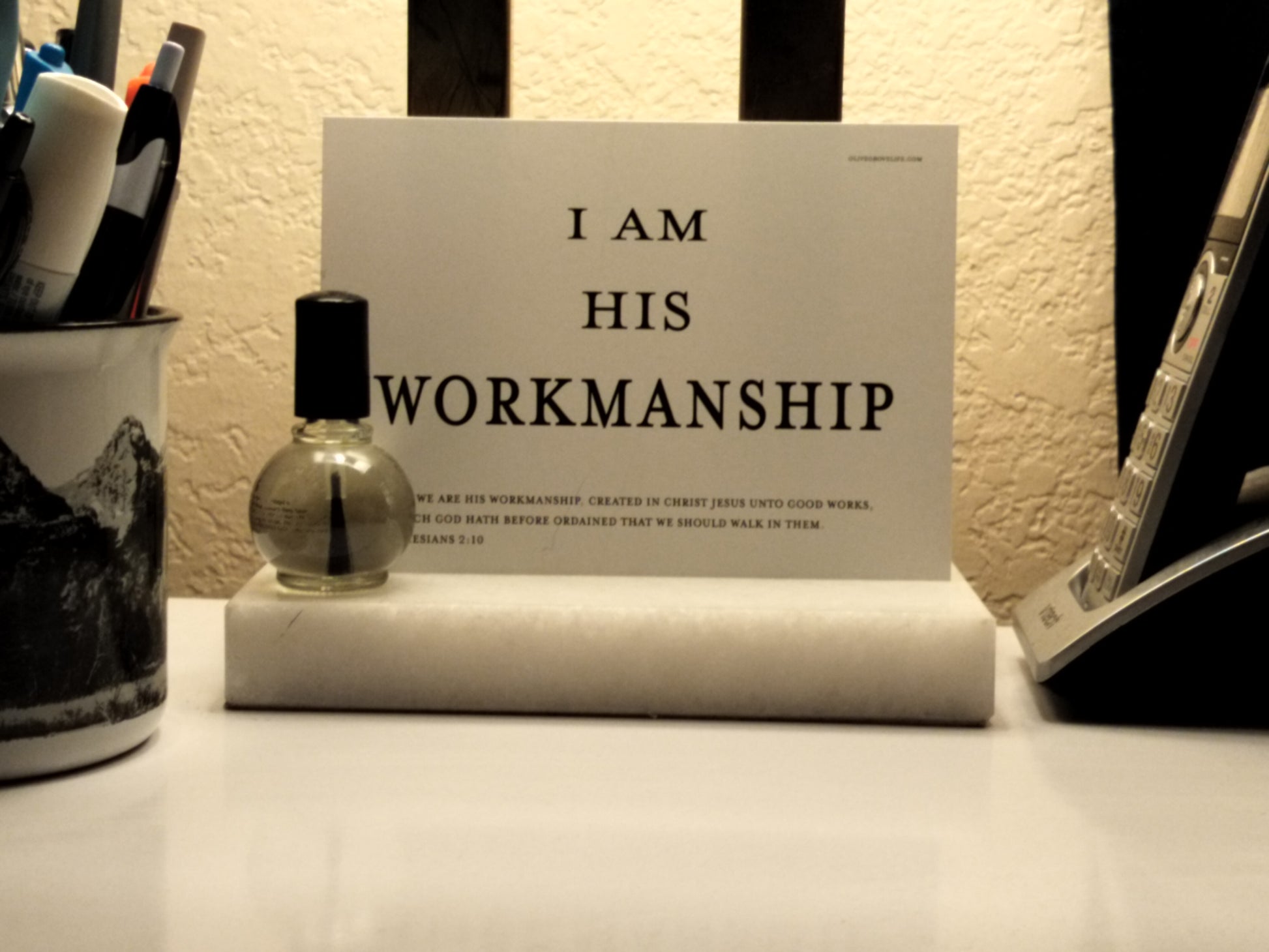 Small bottle of nail polish, roll of paper towels, and sign with text on a surface.